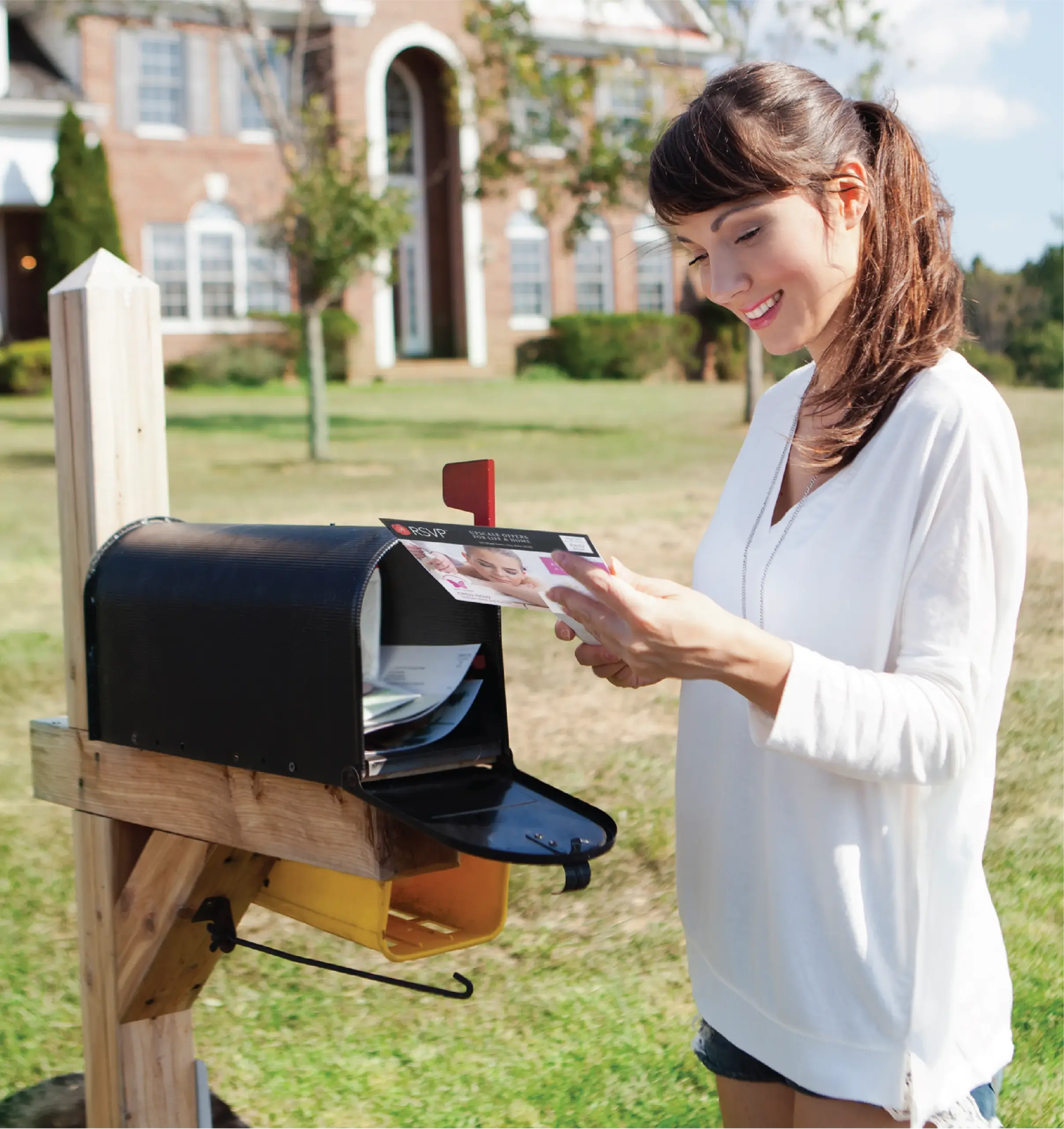 DirectMailIndustry_1 Woman reading a RSVP direct mail advertising unit from her mailbox